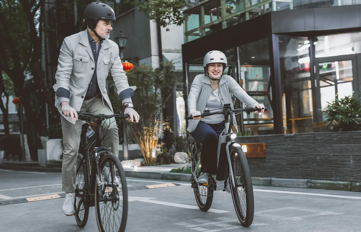A man and woman wearing helmets while riding bikes, demonstrating proper adherence to Bike Lane Rules California.