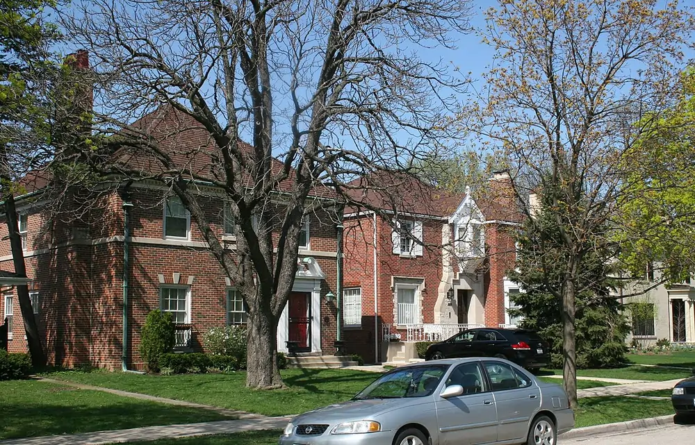 A quiet residential street in Forest Glen, one of the safest neighborhoods in Chicago, with large brick homes and mature trees.