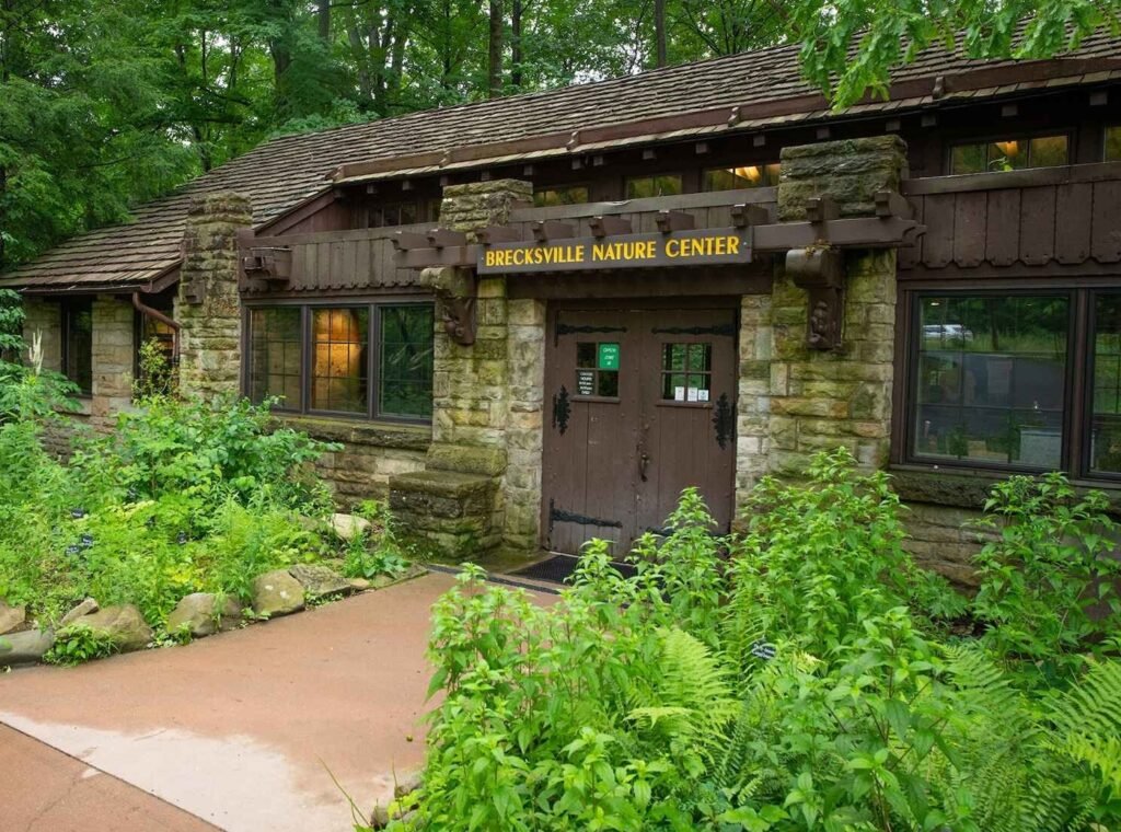 The rustic stone and wood entrance to the Brecksville Nature Center, surrounded by lush ferns and forest, highlighting the community's focus on nature and outdoor recreation.