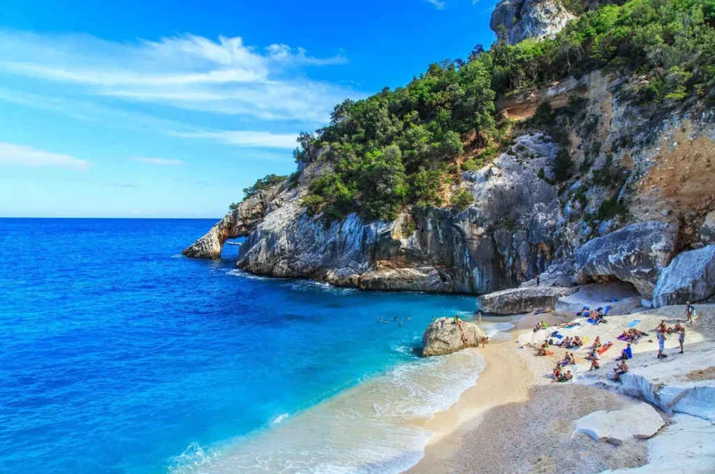 The stunning Cala Goloritzè beach in Sardinia, one of the best summer destinations in Europe, featuring a natural stone arch over incredibly blue water.