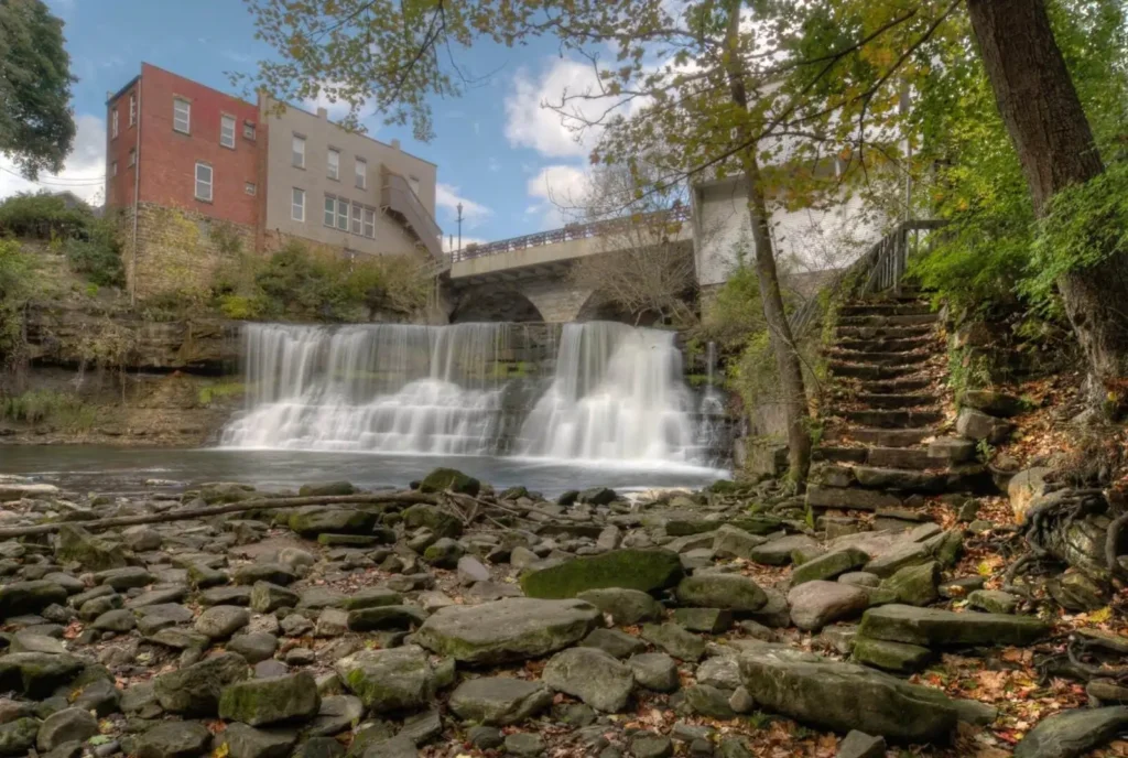 The iconic waterfall in Chagrin Falls, one of the safest neighborhoods in the Cleveland area, with historic buildings and a stone staircase nearby.
