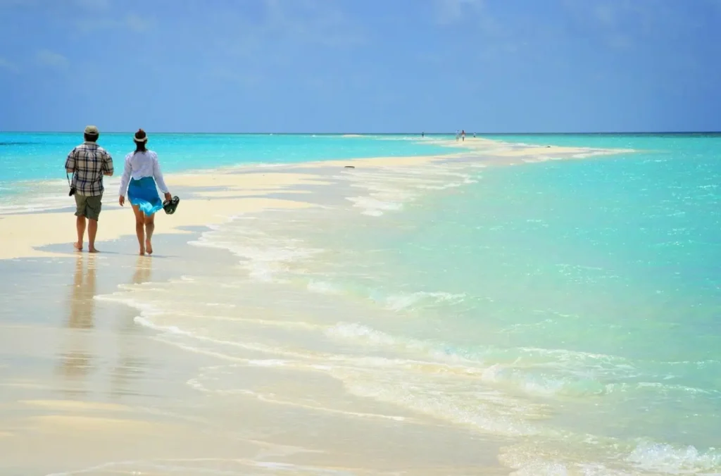 A couple walking on a white sandbar in the Maldives, surrounded by turquoise water, showcasing one of the best destinations in Asia for a honeymoon.