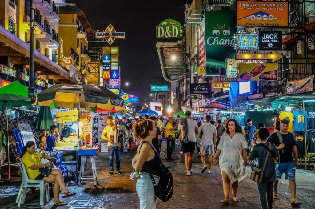A bustling night scene on Khao San Road in Bangkok, one of the top cities in Asia for nightlife, with crowds of people and bright neon signs.