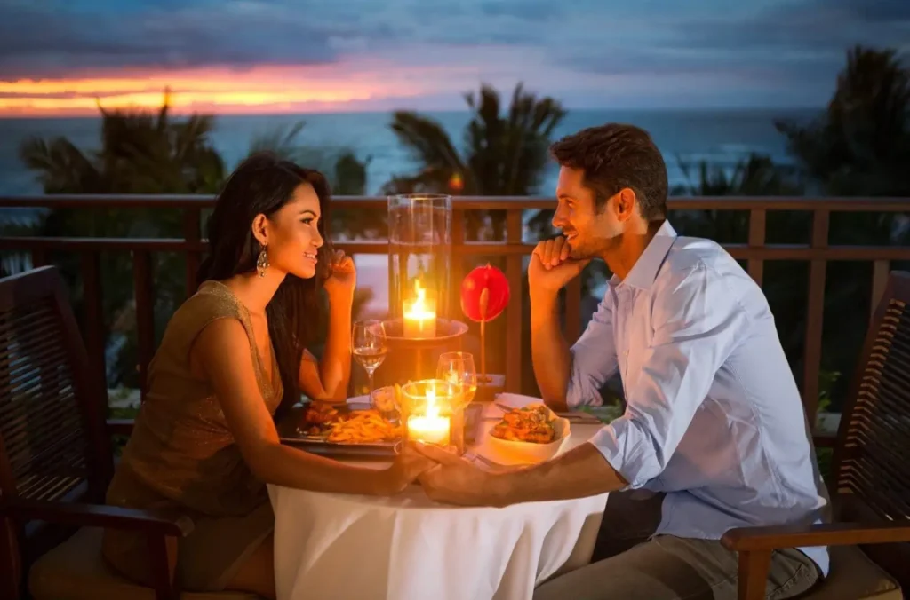 A couple having a romantic candlelit dinner in Bali, one of the best cities in Asia for a honeymoon, with the sunset over the ocean in the background.