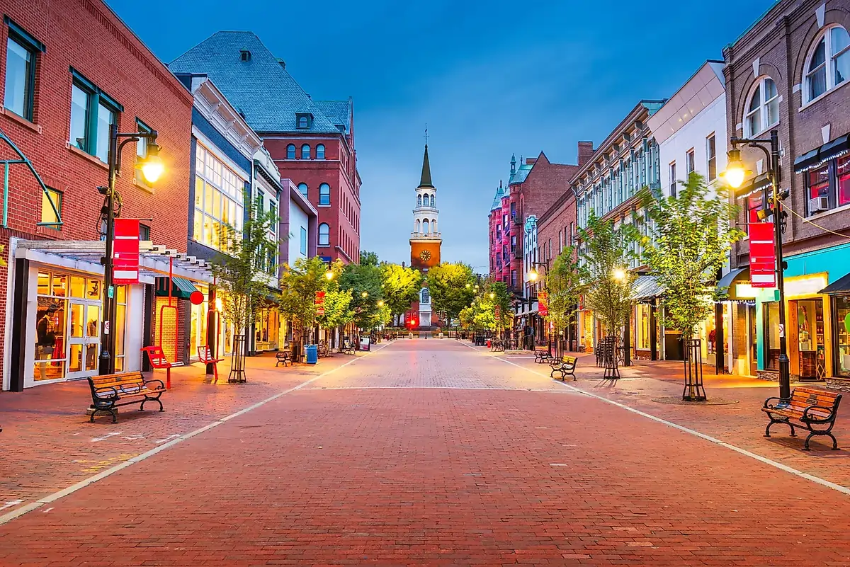 The pedestrian-only Church Street Marketplace in Burlington, Vermont, at twilight, with its brick-paved street, historic buildings, and a church steeple in the distance.