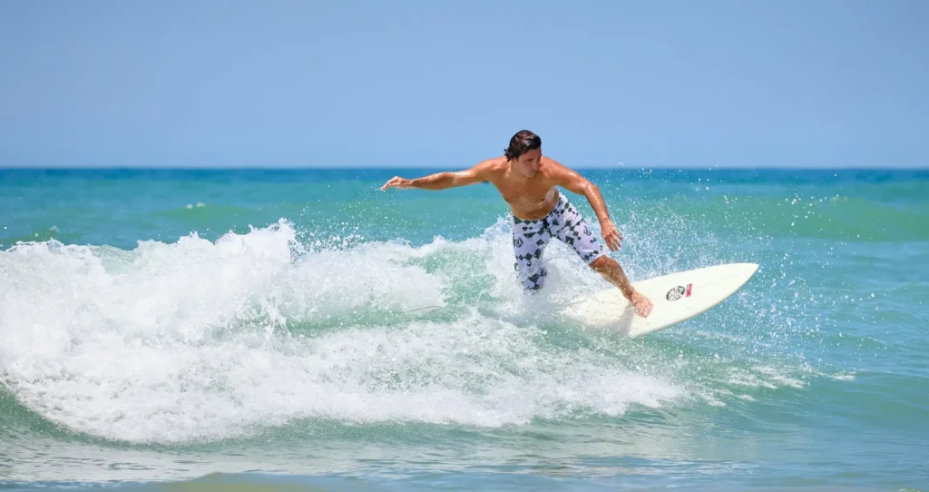 A surfer paddling out on clear waves at Wrightsville Beach, North Carolina, showcasing the beach's appeal for water sports and crystal-clear water