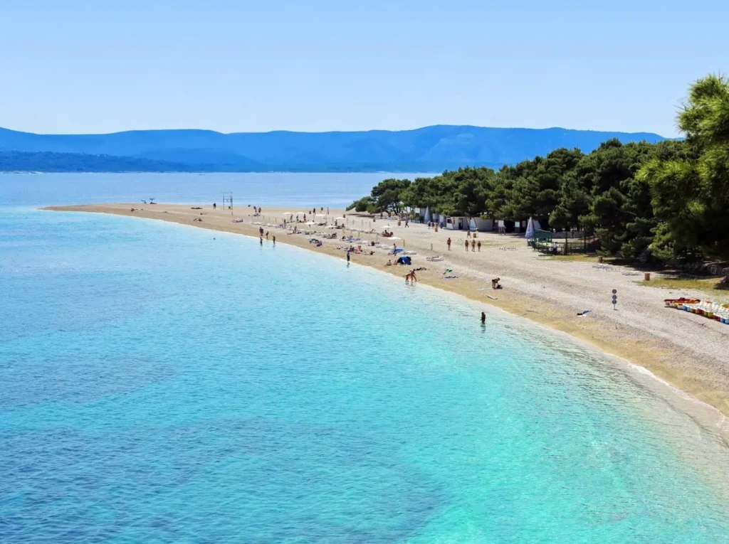 The famous Zlatni Rat beach in Croatia, one of the best summer destinations in Europe, showing its unique V-shape extending into the clear turquoise Adriatic Sea.