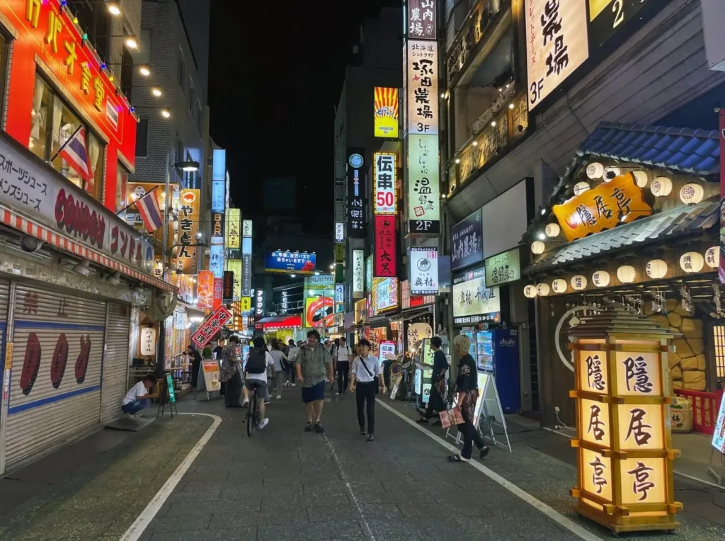 A busy street at night in Shinjuku, Tokyo, one of the top cities in Asia for nightlife, illuminated by countless vertical neon signs.