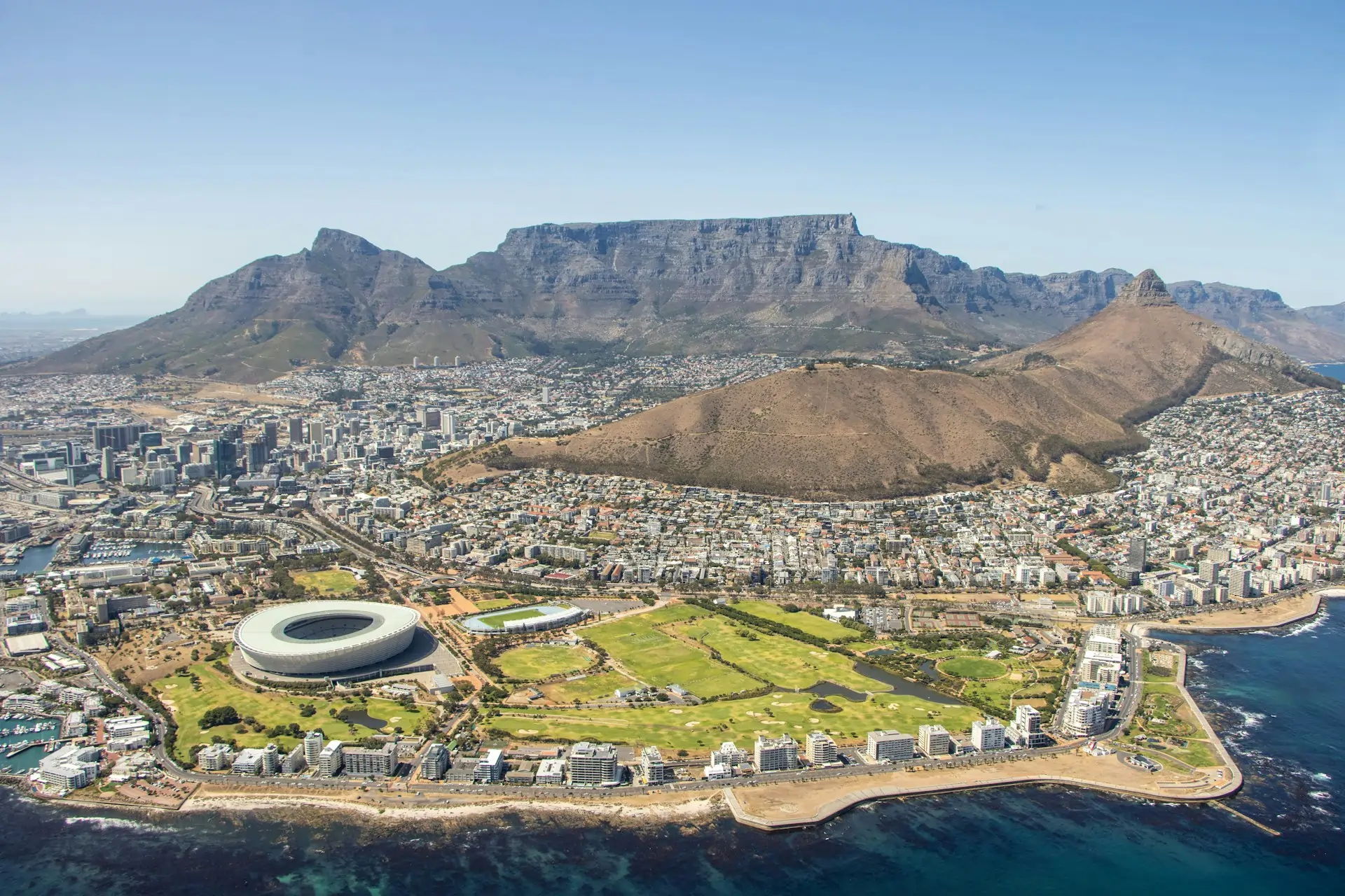 5 Cities in South Africa Where History Comes Alive: An aerial view of Cape Town, one of the most historic cities in South Africa, with Table Mountain in the background and the city stretching to the coast.