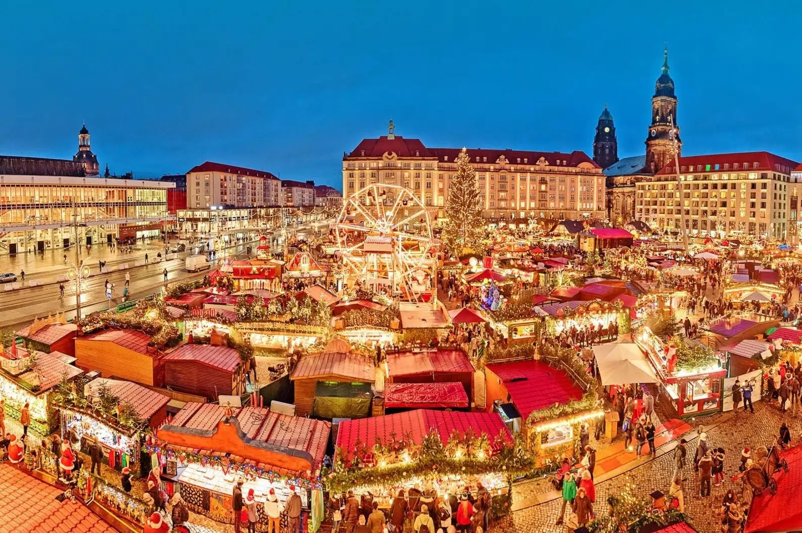 An evening view of the Dresden Christmas Market, one of the best Christmas markets in Europe, with an illuminated Ferris wheel and festive stalls.