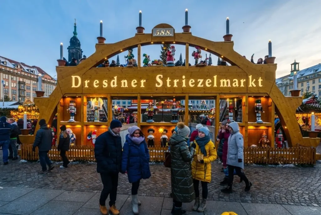 The traditional wooden entrance arch of the Dresdner Striezelmarkt, one of the best Christmas markets in Europe, with visitors in winter clothes.