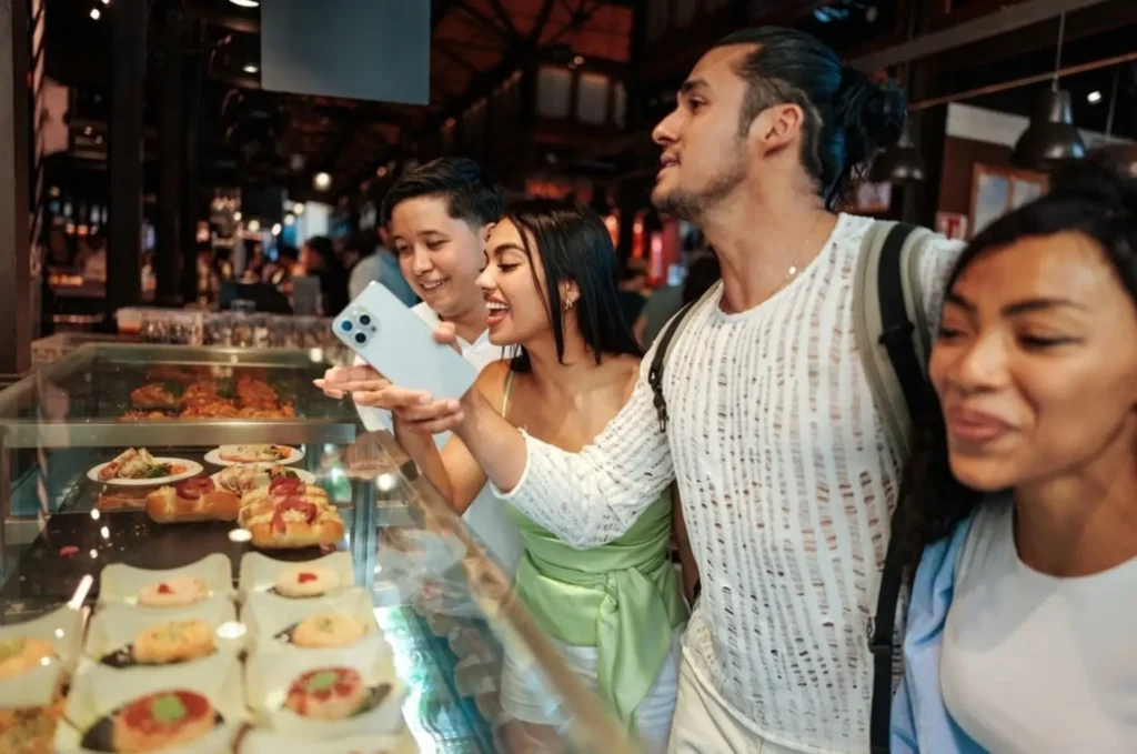 A group of friends on a food tour in Barcelona choosing from a variety of traditional Spanish tapas at a market.