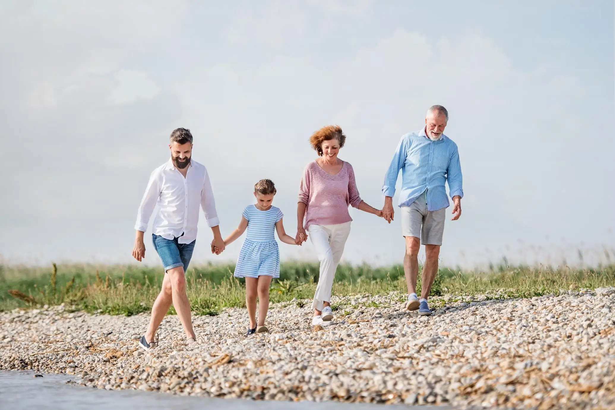 A multi-generational family holding hands and walking together on one of the best family beaches on the East Coast.