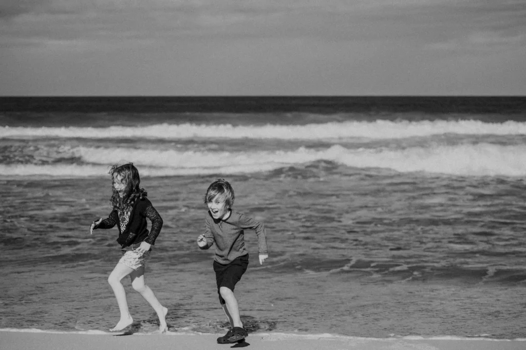 Children playing and running on a sandy family beach, capturing joyful moments at Seabrook Beach, New Hampshire