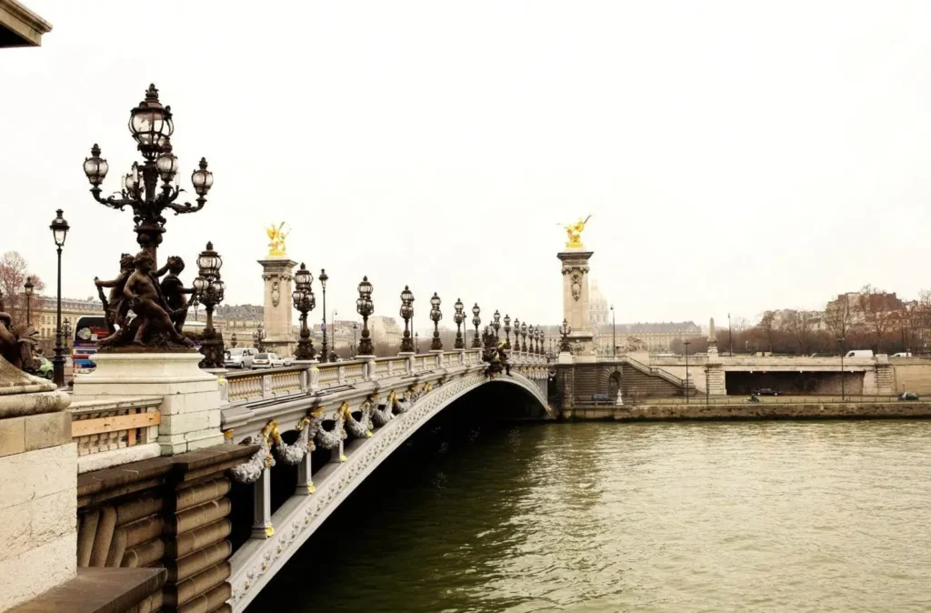 The ornate Pont Alexandre III bridge, a beautiful landmark in Paris, City of Love, crossing the Seine River on an overcast day.