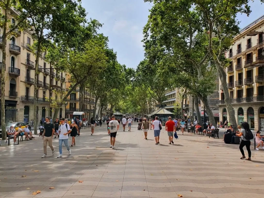 Tourists enjoy walking along La Rambla, the iconic pedestrian street in Barcelona, known for its vibrant atmosphere and historic architecture